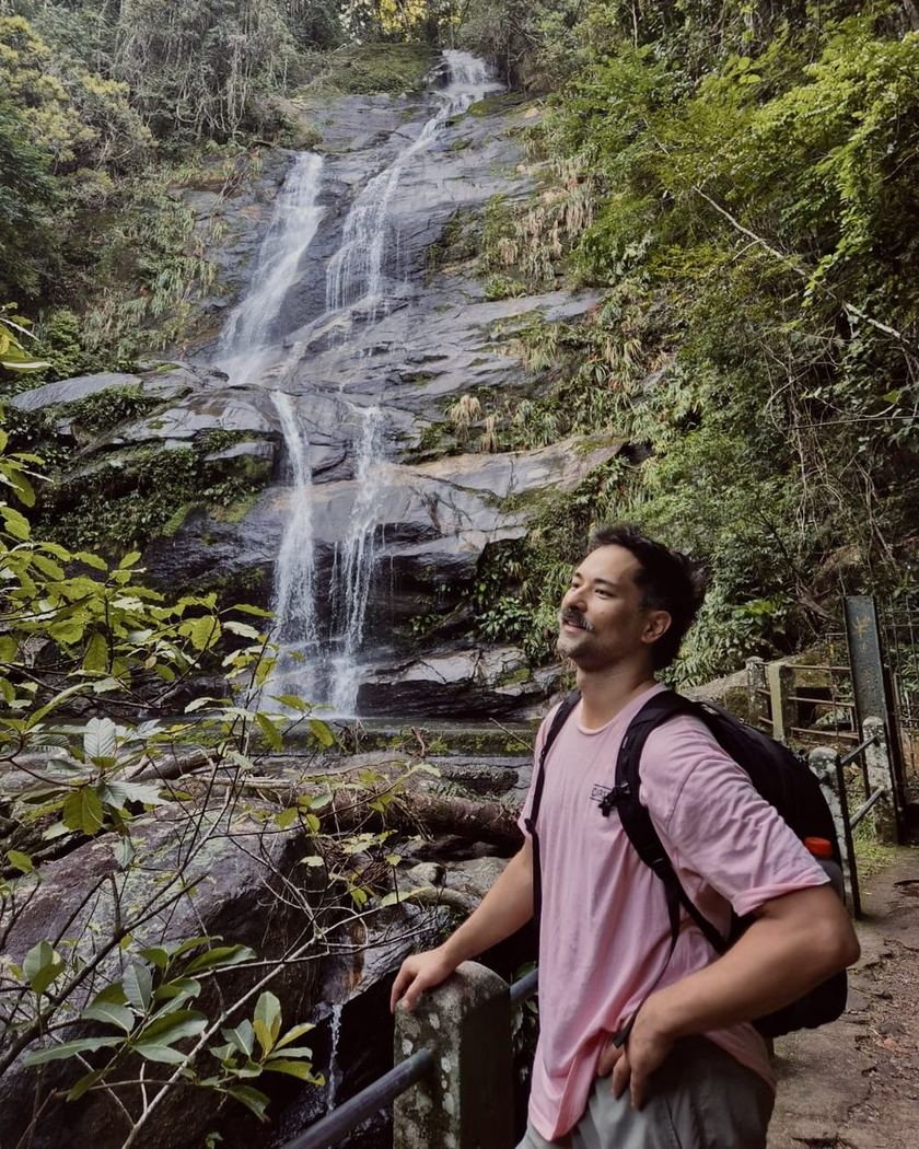 Jacob Ando standing by a waterfall in the forest
